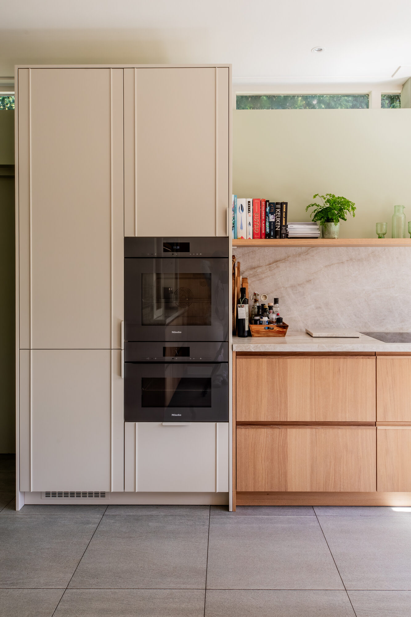 Hoge kastenwand met ingebouwde Miele ovens naast de eiken keuken