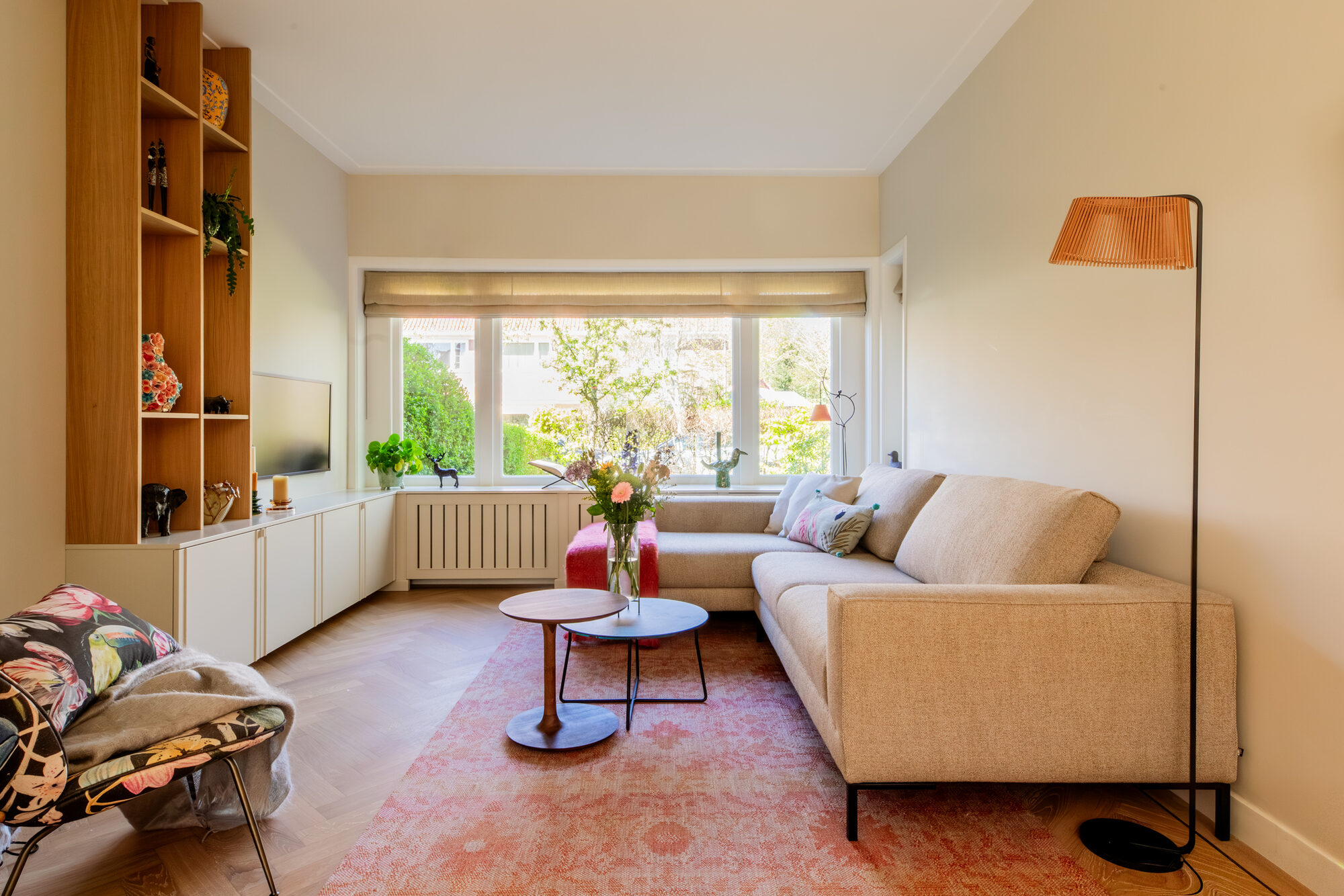 Woonkamer met bank, maatwerk kastenwand en staande lamp