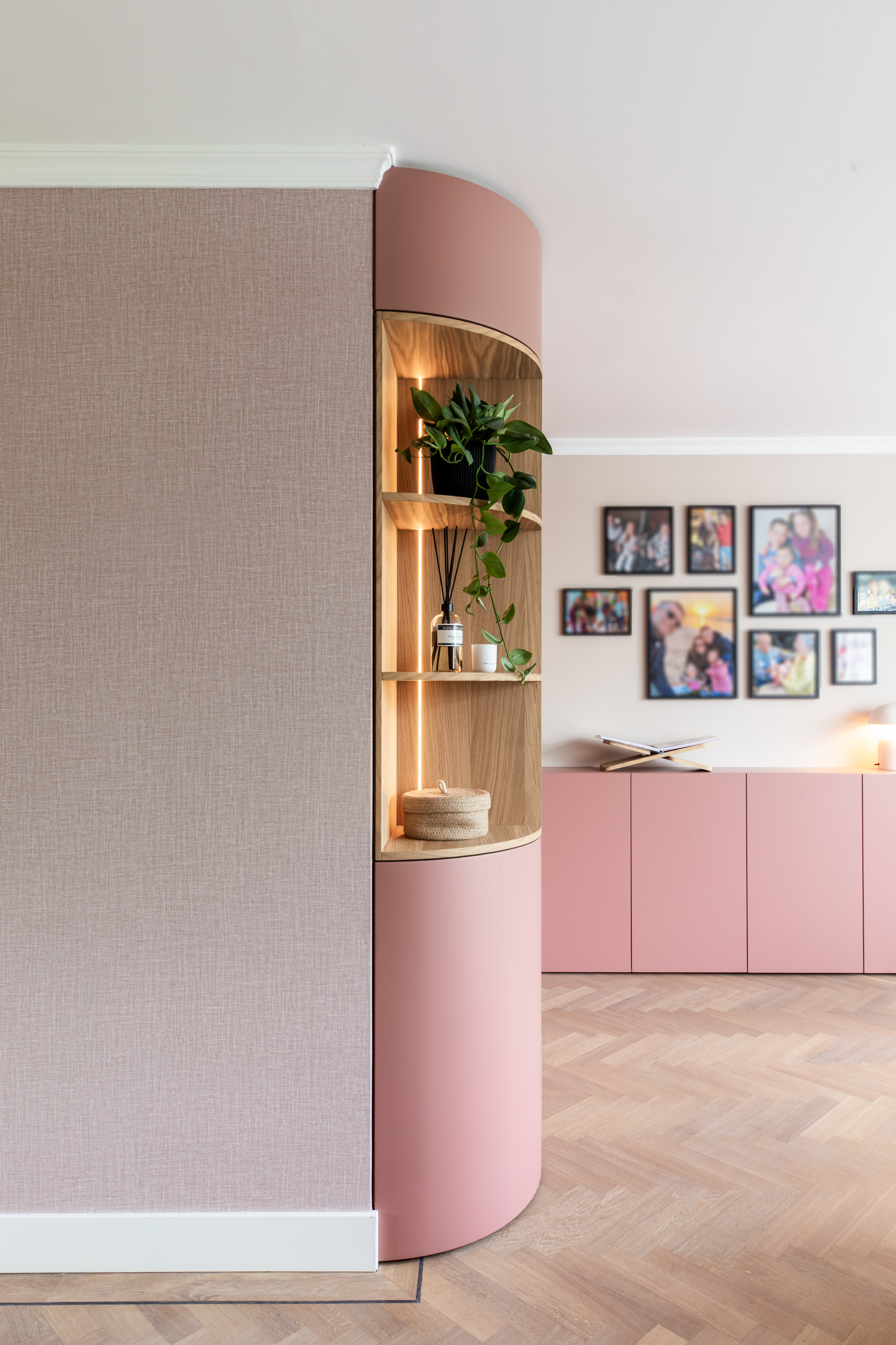 Ronde hoek van de terra-roze maatwerkkast met verlichte eiken nis en linnenlook behang, interieurontwerp woning Bennebroek door Authentic Interiors