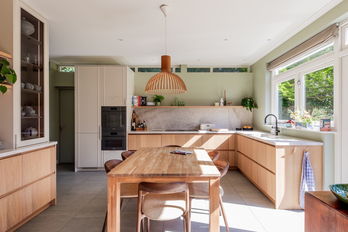 De gerealiseerde keuken in Overveen, in zachtgroen met eikenhout, kwartsiet en een houten eettafel