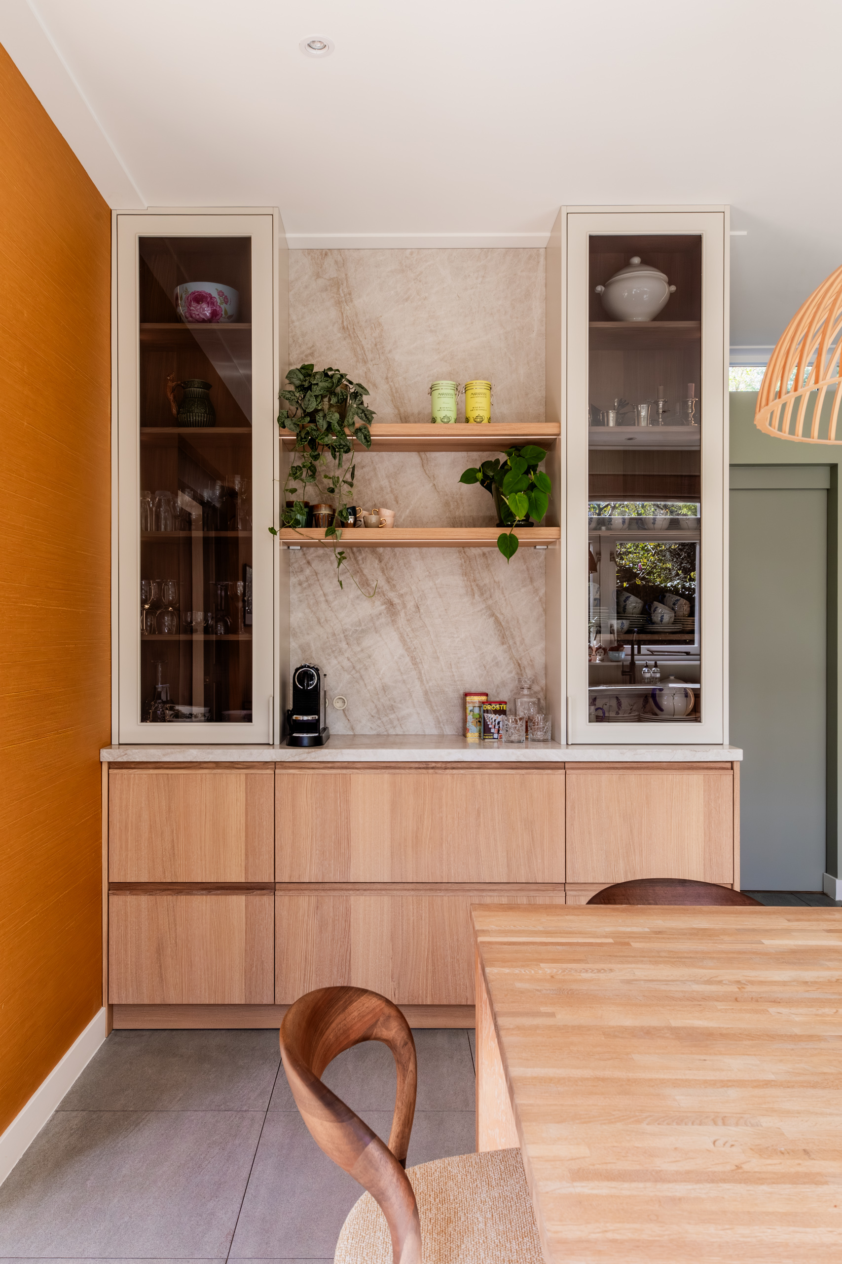 Maatwerk servieskast met vitrinedeuren en natuurstenen achterwand naast een cognackleurige wand, jaren 30 woning in Overveen, ontwerp Authentic Interiors