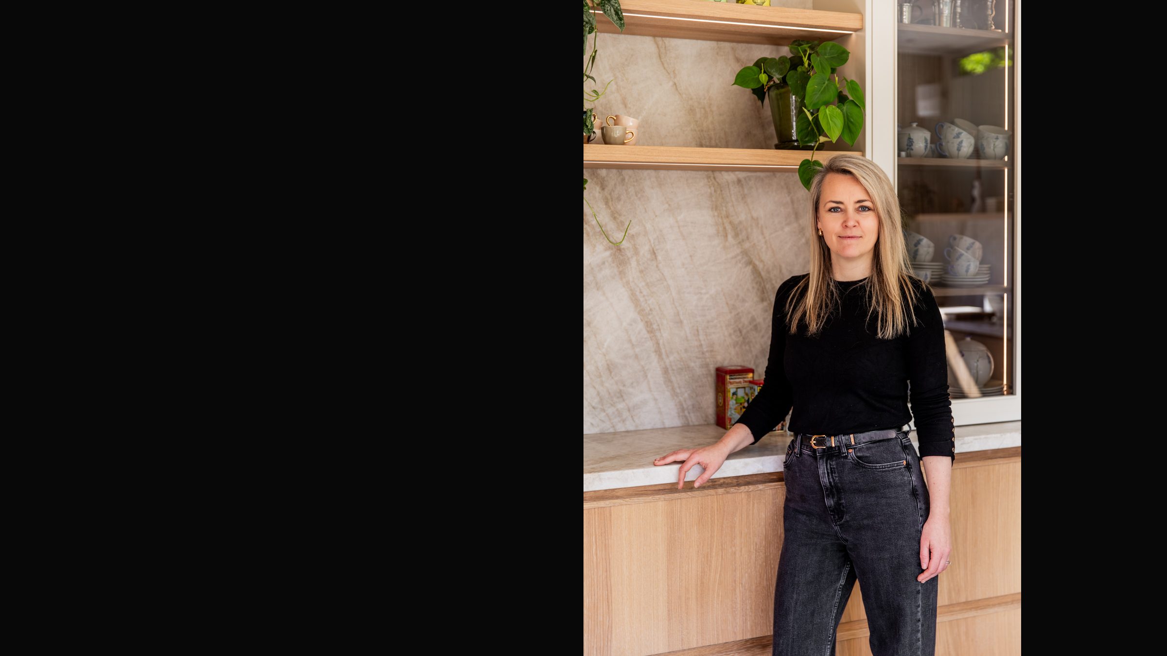 Lisette van de Wouw, interieurontwerper, in een keuken met natuurstenen achterwand en eiken kasten die ze ontwierp in Overveen